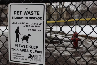 An image of a white sign with black text " PET WASTE TRANSMITS DISEASE LEASE, CURB AND CLEAN UP AFTER YOUR PET IT'S THE LAW PLEASE KEEP THIS AREA CLEAN. $50 FINE PER CITY ORDINANCE SECTION 16-1.10A BOSTON PARKS AND RECREATION."